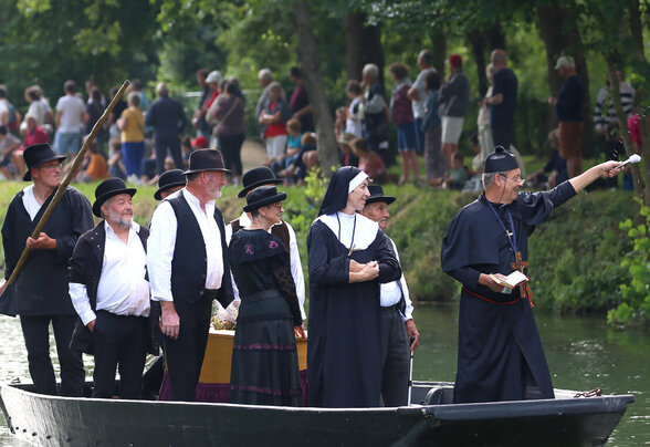 Participants en costumes maraîchins naviguant en barque sur un canal, sous le regard d'un public nombreux sur la berge - Agrandir l'image, fenêtre modale
