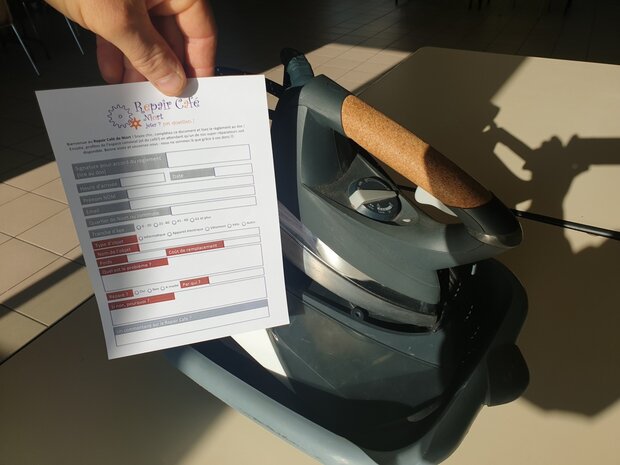 Formulaire d'accueil du Repair Café Niort tenu devant un fer à repasser apporté en réparation