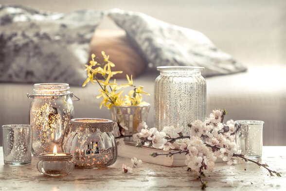 Composition de bougeoirs en verre argenté avec une bougie allumée et des branches de fleurs blanches sur une table - Agrandir l'image, fenêtre modale