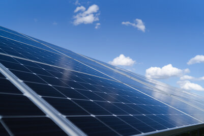 Rangées de panneaux solaires photovoltaïques en gros plan, inclinés et exposés sous un ciel bleu clair