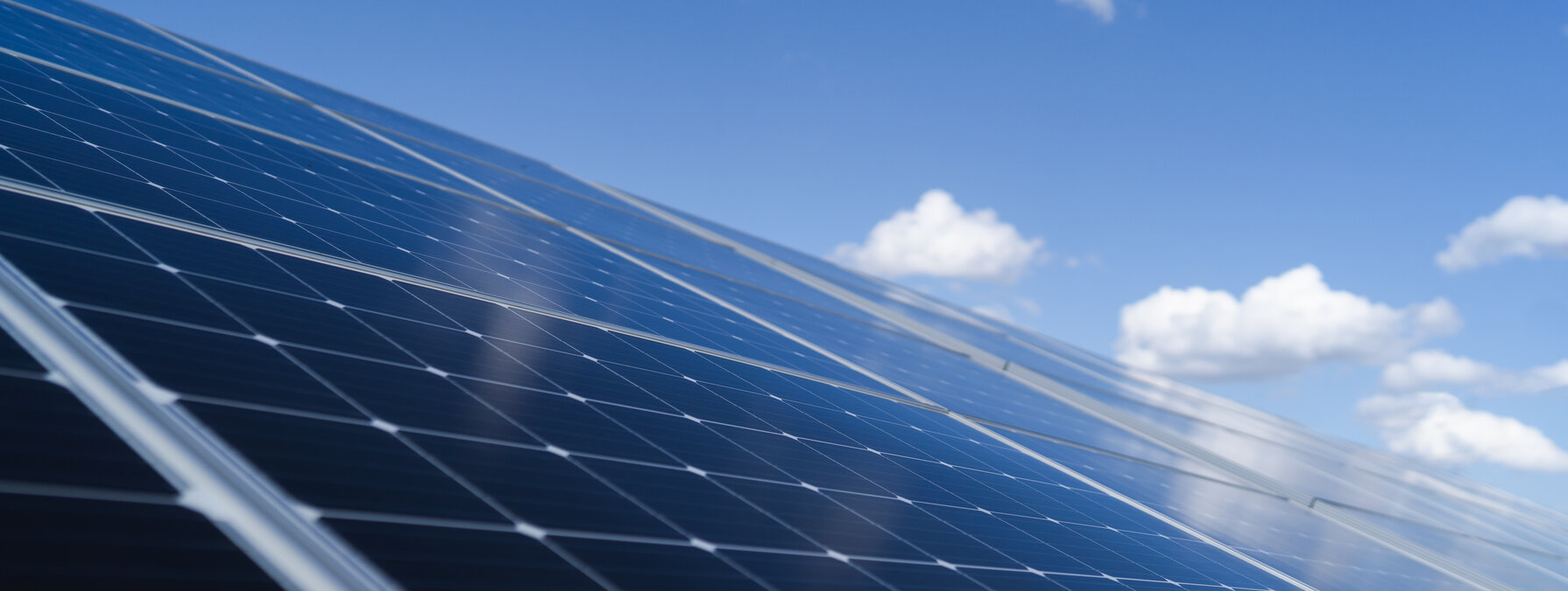 Rangées de panneaux solaires photovoltaïques en gros plan, inclinés et exposés sous un ciel bleu clair