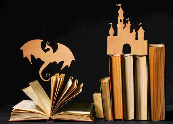 Livres ouverts ornés de silhouettes en papier découpé représentant un dragon et un château de conte - Agrandir l'image, fenêtre modale