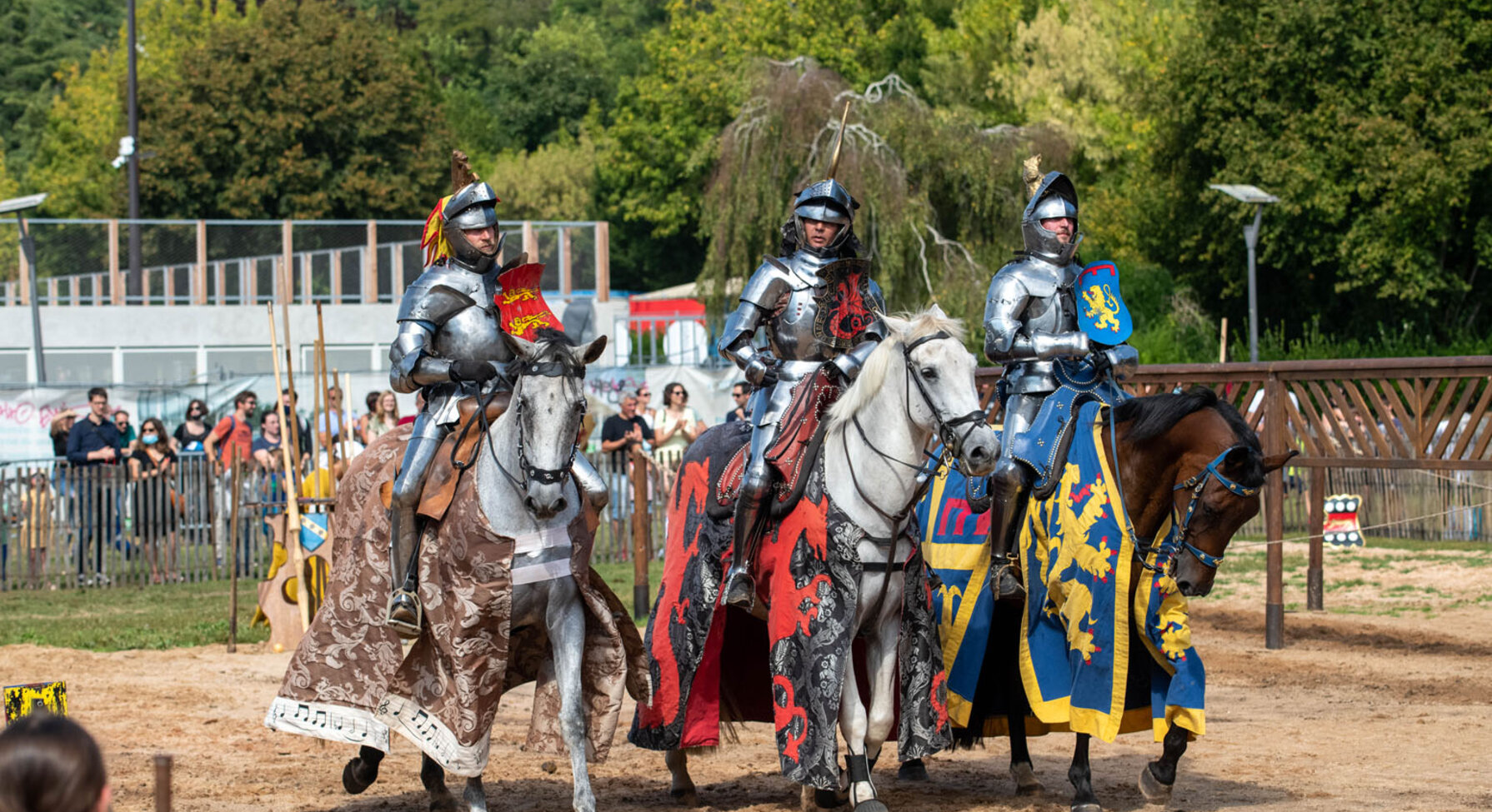 Trois chevaliers en armure montés sur des chevaux caparaçonnés lors d'un spectacle équestre médiéval