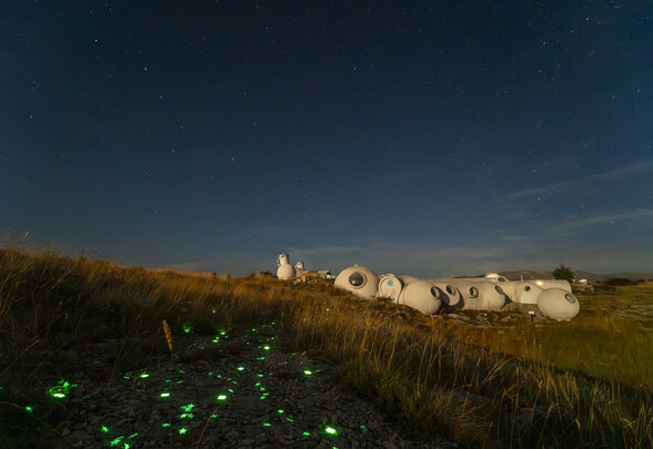 Structures en forme de dômes blancs illuminées la nuit sous un ciel étoilé, avec des lumières vertes en forme d'étoiles au sol - Agrandir l'image, fenêtre modale