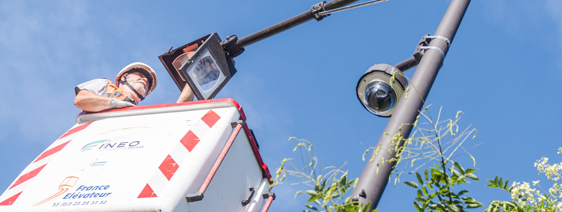 Technicien en nacelle élévatrice réalisant une intervention de maintenance sur un poteau d'éclairage public