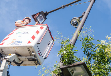 Technicien en nacelle élévatrice réalisant une intervention de maintenance sur un poteau d'éclairage public
