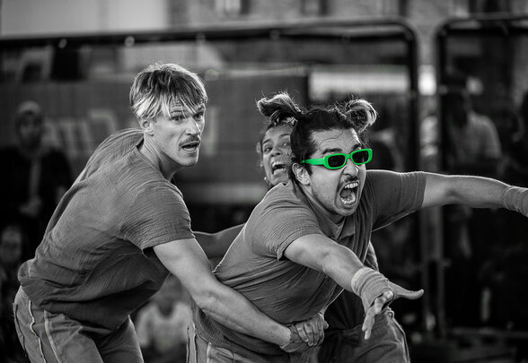 Trois artistes de la Cie Les Lulus en pleine action acrobatique, l'un portant des lunettes vertes fluorescentes - Agrandir l'image, fenêtre modale