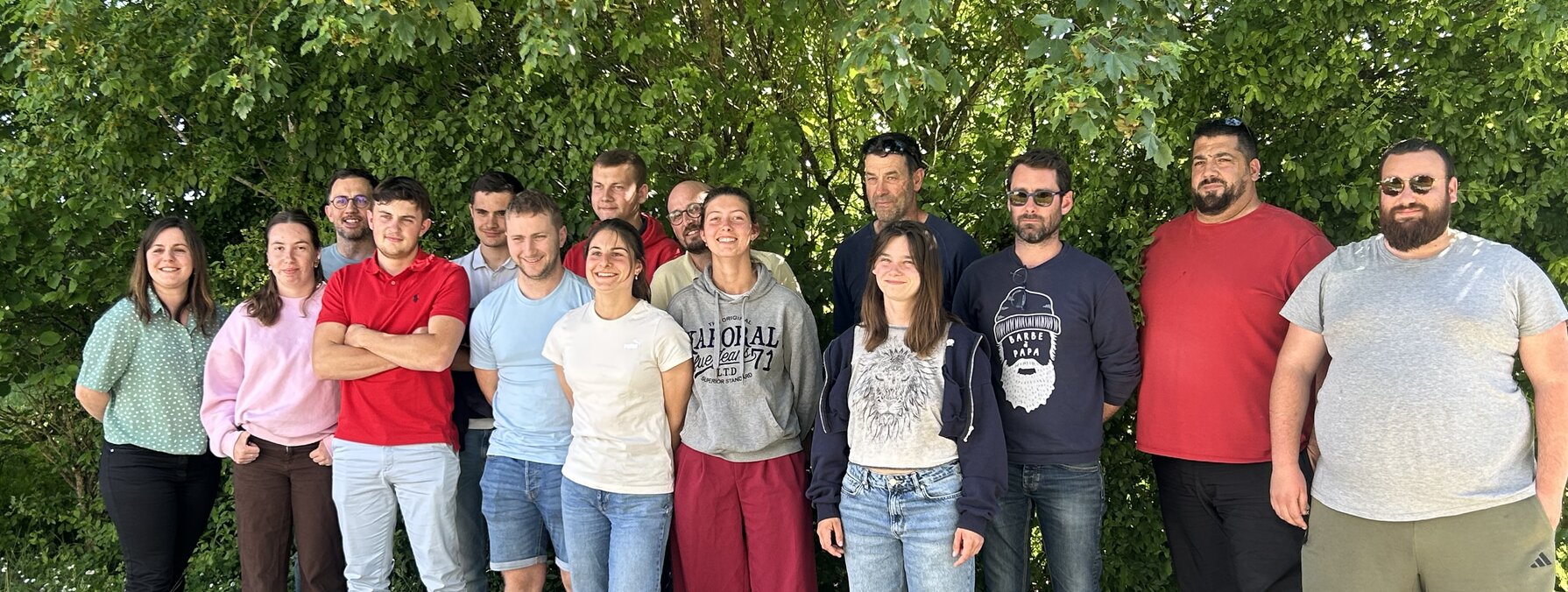Groupe d'environ quinze participants au projet, posant ensemble en extérieur après la réunion bilan.
