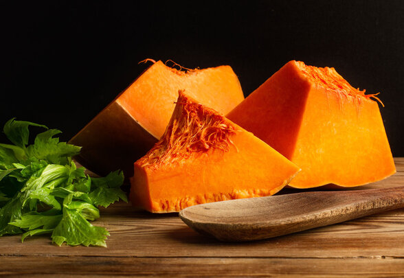 Morceaux de courge à la chair orange vive, feuilles de céleri et cuillère en bois sur une planche rustique - Agrandir l'image, fenêtre modale