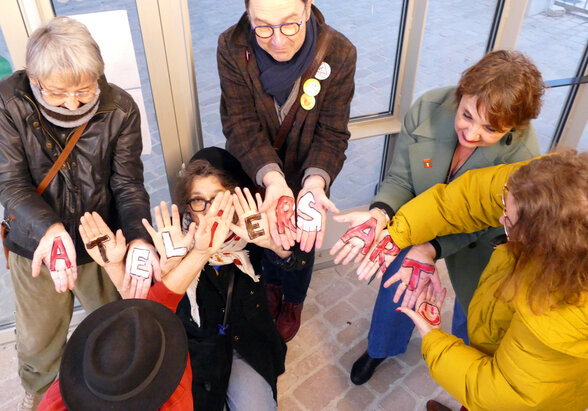 Membres de l'association, mains tendues formant les mots « Ateliers Artistes » peints lettre par lettre sur leurs paumes. - Agrandir l'image, fenêtre modale