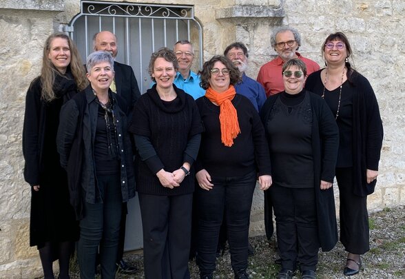 groupe de l'ensemble vocal DeuxPlus et Compagnie, dix chanteurs souriants devant un mur en pierre - Agrandir l'image, fenêtre modale