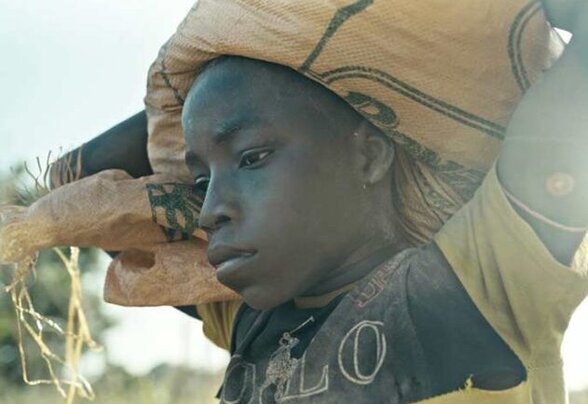 Opio, jeune travailleur de la mine, porte un lourd sac de jute sur la tête et regarde l'objectif avec gravité - Agrandir l'image, fenêtre modale