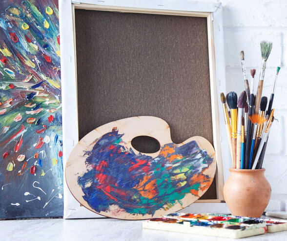Palette de peintre colorée, pinceaux regroupés dans un pot en terre cuite et toiles devant un mur de briques blanches - Agrandir l'image, fenêtre modale