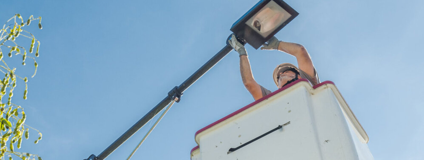 Technicien casqué en nacelle élévatrice procédant à l'installation d'un luminaire d'éclairage public