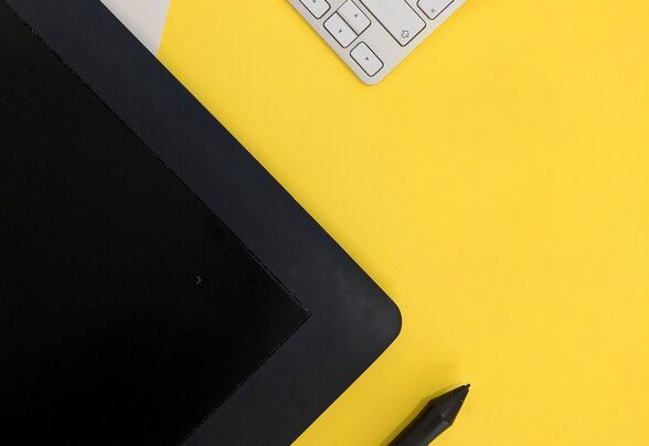 Clavier blanc et tablette graphique noire avec stylet, posés sur un fond jaune vif - Agrandir l'image, fenêtre modale