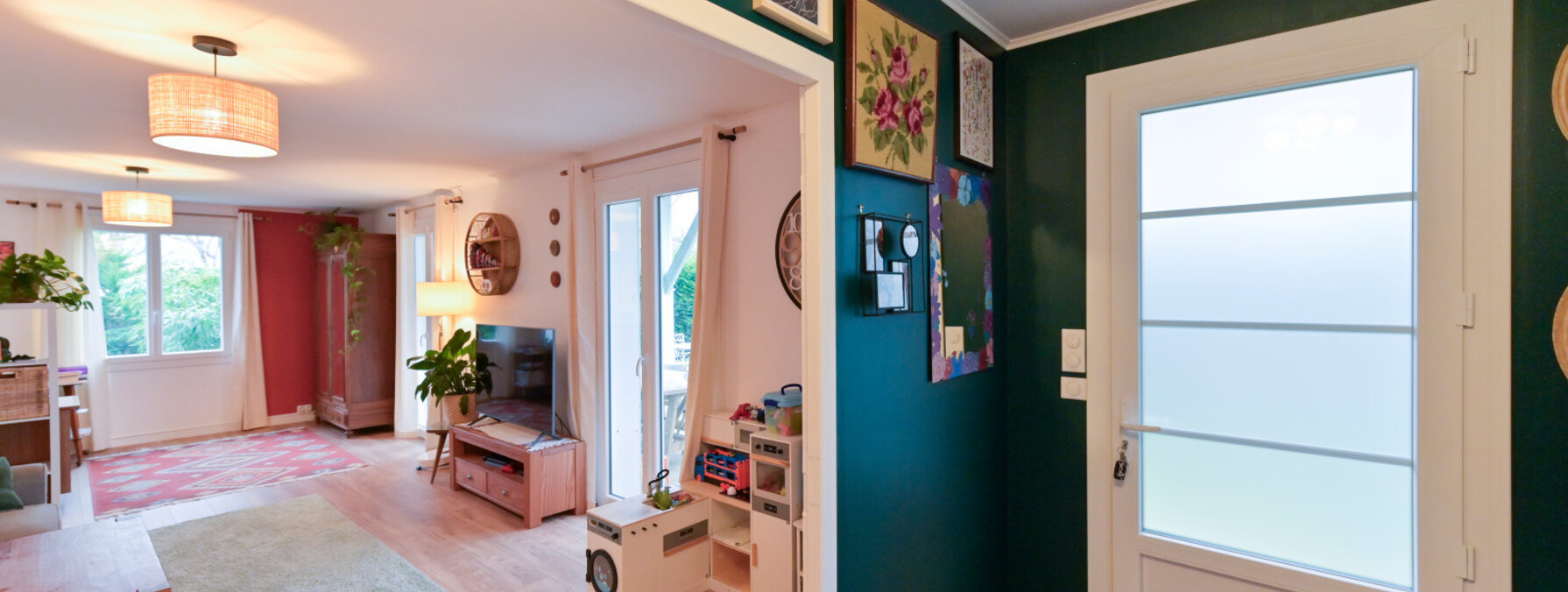 Entrée et salon d'un logement résidentiel aux murs vert foncé, parquet clair et décoration personnalisée