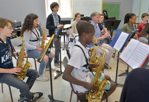 Groupe d'élèves jouant du saxophone et de la clarinette sur partitions, accompagnés par un professeur