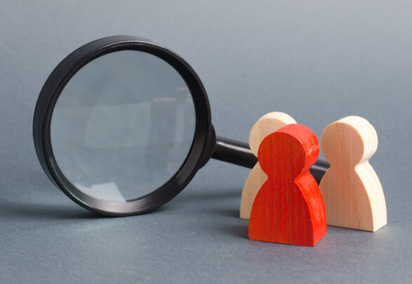 Three wooden human figure stands near a magnifying glass on a gray background. Search for vacancies and work. Human resources, management. The concept of the search for people and workers. - Agrandir l'image, fenêtre modale