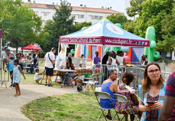 Participants de tous âges rassemblés en plein air autour des tentes du CSC du Parc, château gonflable et stands d'animation visibles. - Agrandir l'image, fenêtre modale