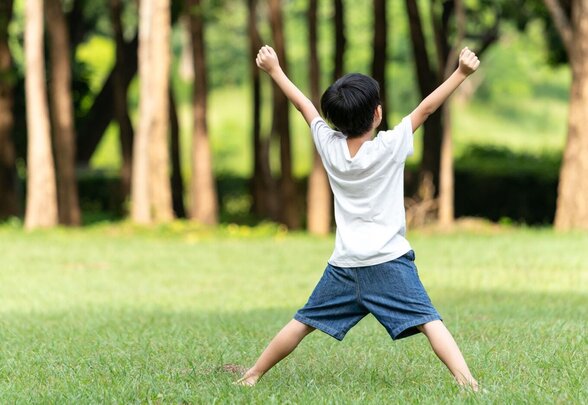 Enfant bras levés en signe de victoire dans un parc verdoyant - Agrandir l'image, fenêtre modale