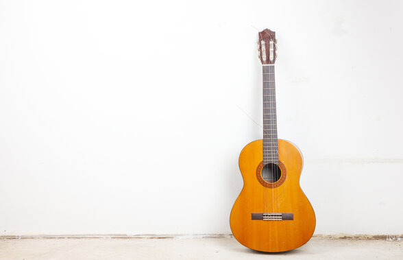 Guitare classique à cordes nylon posée contre un mur blanc - Agrandir l'image, fenêtre modale