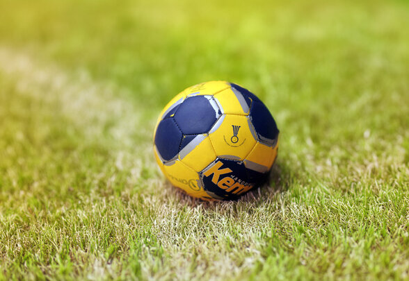 Ballon de handball Kempa jaune et marine posé sur une pelouse verte - Agrandir l'image, fenêtre modale