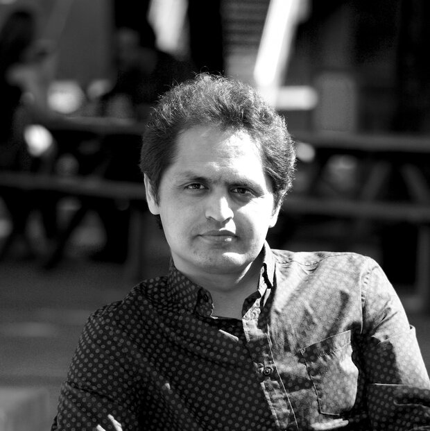 Khosraw Mani, journaliste et romancier, les bras croisés dans un espace extérieur