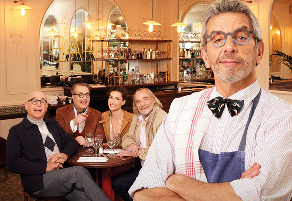 Affiche officielle : Michel Cymes en tablier au premier plan, quatre acteurs attablés dans un décor de restaurant parisien - Agrandir l'image, fenêtre modale