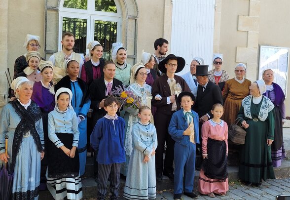 Membres de l'association en costumes d'époque du XIXe siècle réunis en groupe devant un bâtiment en pierre pour le marché traditionnel - Agrandir l'image, fenêtre modale