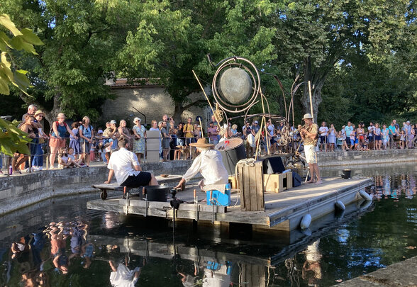Musiciens sur radeau flottant avec gong géant lors d'une création sonore devant un public nombreux sur les berges de la Sèvre - Agrandir l'image, fenêtre modale